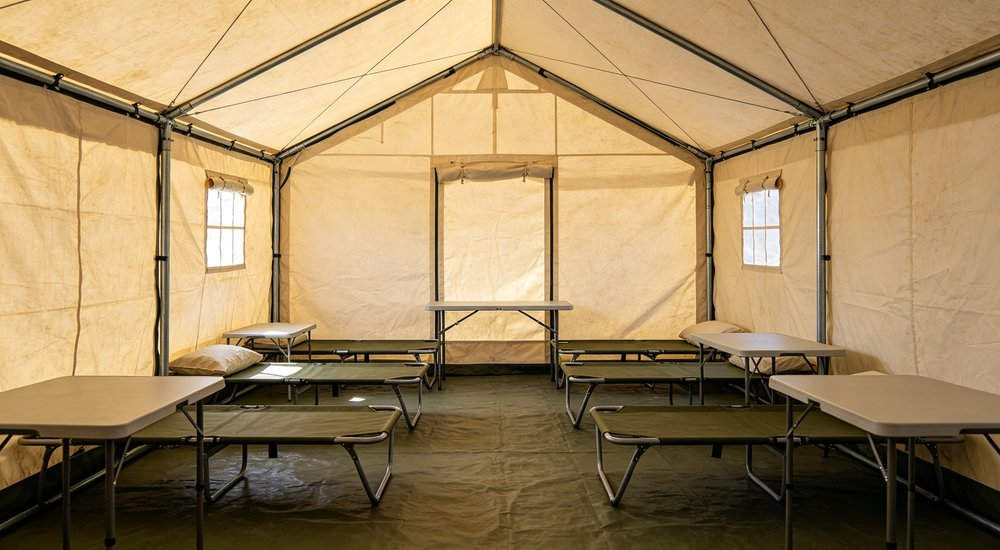 Interior of twelve square meter steel frame relief tent with support poles, traditional shelter layout with structural columns, interior photography