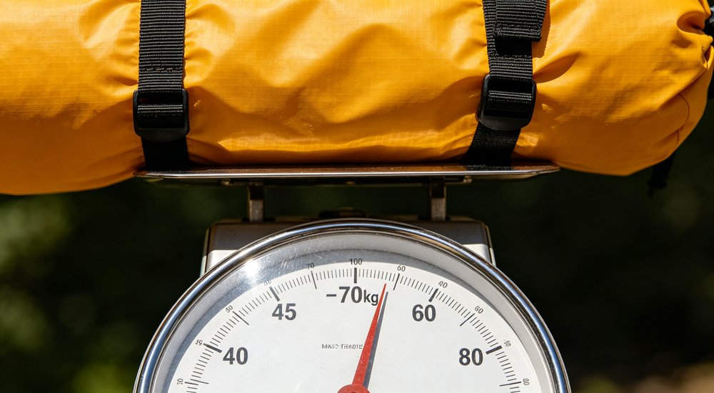 Inflatable tent weight showing worker carrying compact bag, green grass red and white inflatable emergency shelter for disaster relief operations