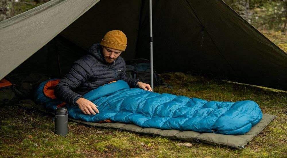 Wide angle view of sleeping bag sample testing evaluator testing in real world shelter setting hands on
