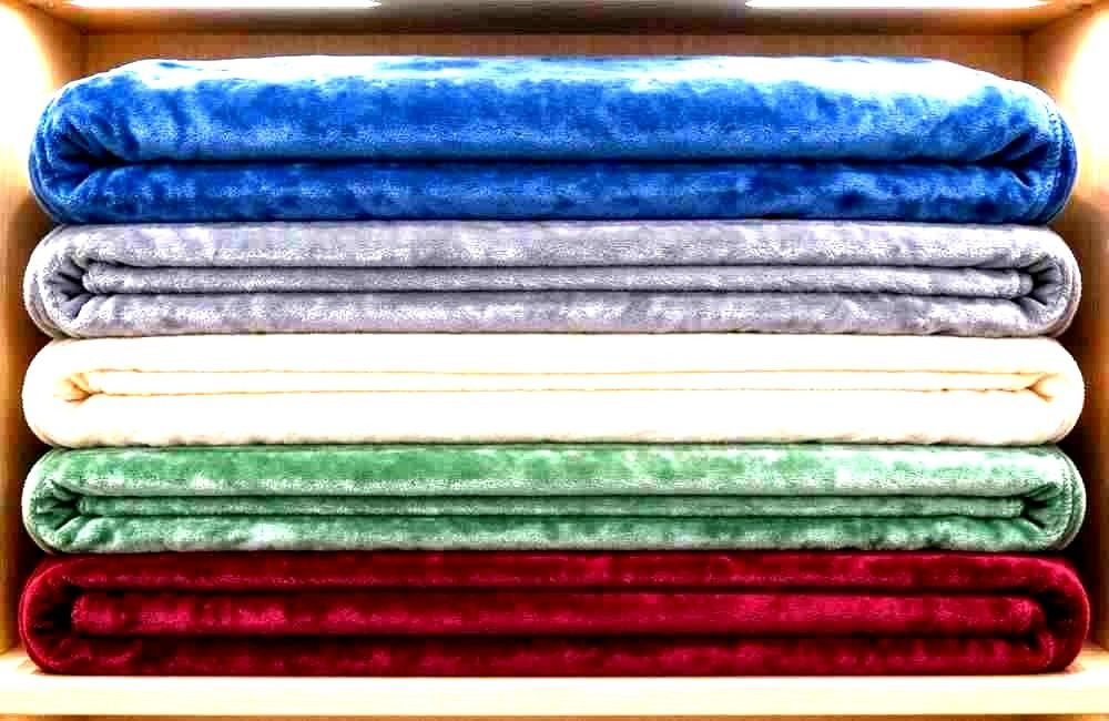 Product view of colourful flannel blankets stacked in neat piles in a bright showroom, saturated colours, full frame, no people